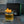 Load image into Gallery viewer, Glass of amber liquid with a skewer of orange peel on a dark tiled surface, featuring Pressice Barware branding.